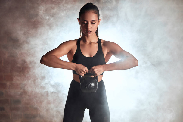 Sporty woman stand holding kettlebell - 写真・画像
