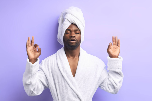 Spokojny Afrykanin uprawiający jogę i medytujący na fioletowym tle hitu - Zdjęcie, obraz