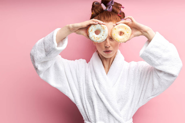 lovely girl in home clothes posing with donuts on pink background - Fotoğraf, Görsel
