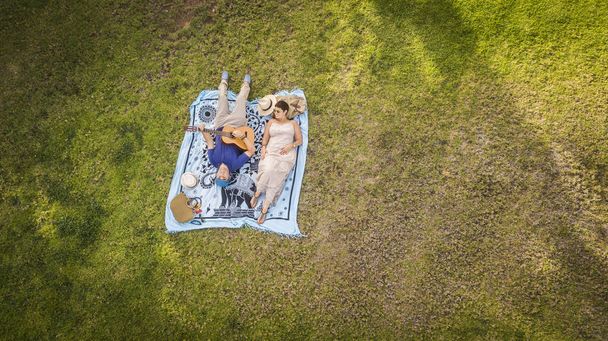пара з двох дорослих лежала на траві насолоджуючись відпочинком на відкритому повітрі разом
  - Фото, зображення