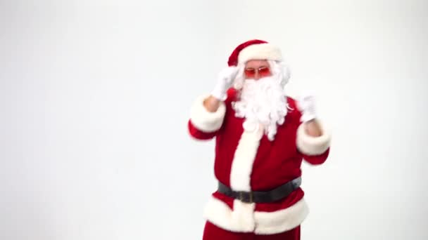Christmas. Santa Claus on a white background in pink glasses in the shape of a heart is dancing and showing a heart with his hands. Love and happiness. - Filmmaterial, Video
