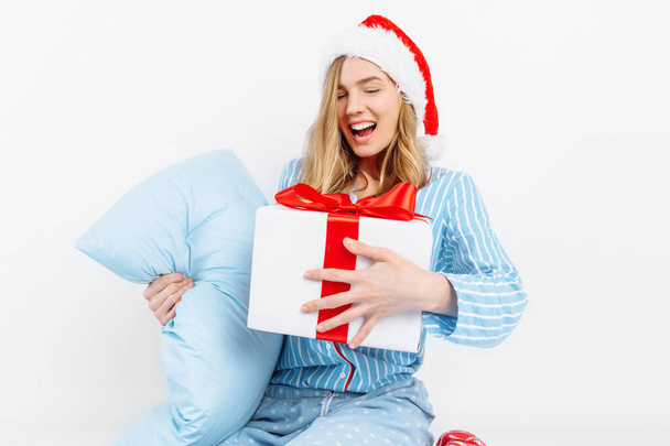 Christmas morning. Happy beautiful young girl, in Christmas pajamas and Santa hat, received a gift on Christmas day - Fotoğraf, Görsel