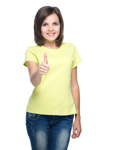 Attractive young woman in a yellow shirt and blue jeans. Showing - Foto, imagen