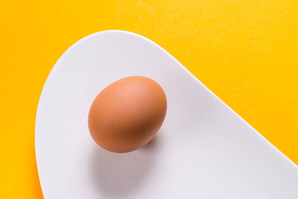 Boiled egg on white porcelain plate on yellow background - 写真・画像