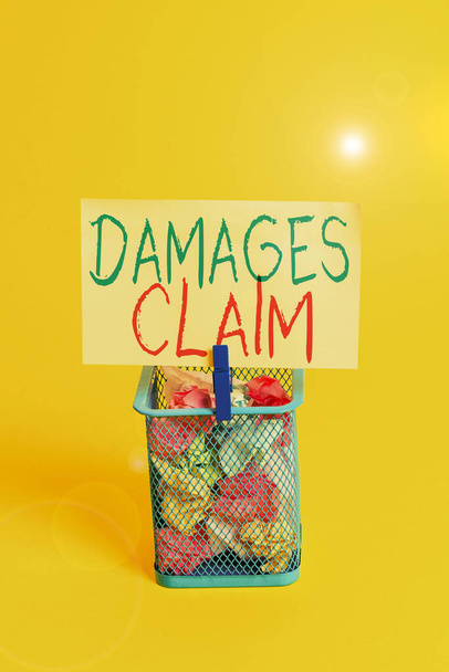 Handwriting text Damages Claim. Concept meaning Deanalysisd Compensation Litigate Insurance File Suit Trash bin crumpled paper clothespin empty reminder office supplies yellow. - Photo, Image
