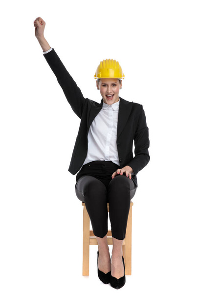 zakenvrouw dragen van gele helm en het houden van een vuist omhoog - Foto, afbeelding