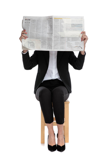 shy businesswoman sitting and hiding behind newspaper - Foto, Bild