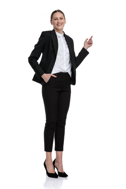businesswoman standing with hand in pocket and pointing up - Fotografie, Obrázek