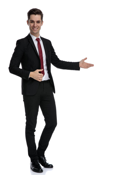 Positive young businessman presenting to the side  - Photo, image