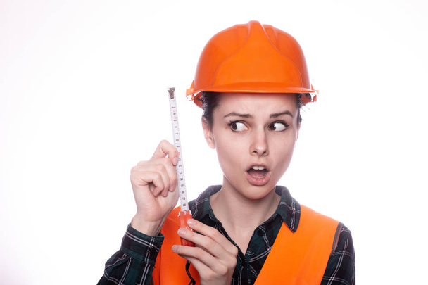 beautiful young girl worker in a helmet holds a measuring tape in hand - Fotoğraf, Görsel