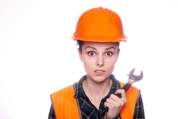 beautiful young girl worker in a helmet holds in her hand a wrench - Foto, imagen