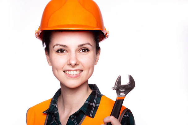 beautiful young girl worker in a helmet holds in her hand a wrench - Foto, Bild