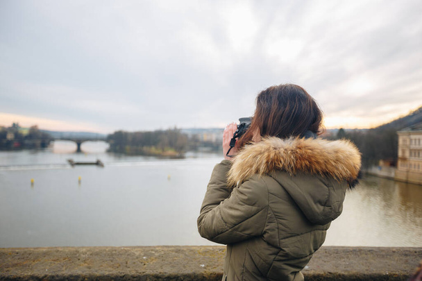 Nainen ottaa kuvia Kaarlen sillalla Prahassa. Nuori kaunis tyttö turisti seisoo Kaarlen sillalla Prahassa Tsekin tasavallassa ja ottaa kuvia kauniista kaupunkinäkymistä
 - Valokuva, kuva