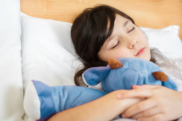 dívka spí s měkkou hračkou na bílé posteli - Fotografie, Obrázek