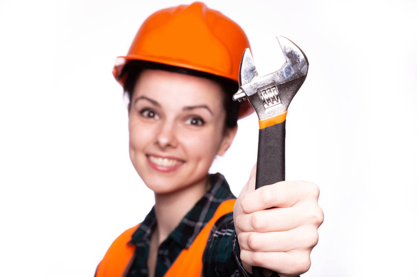 beautiful young girl worker in a helmet holds in her hand a wrench - Foto, Bild
