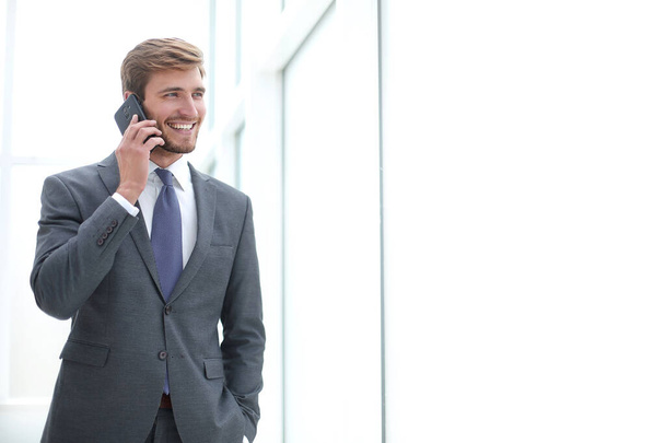 businessman talking on a mobile phone standing near the office window - Valokuva, kuva
