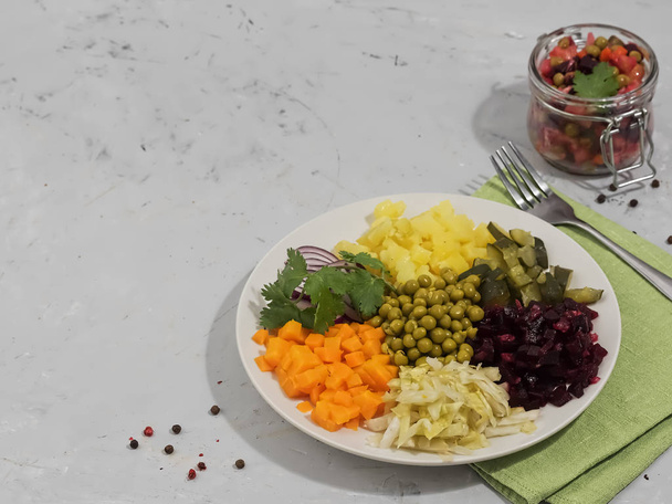 Saladeingrediënten op een bord. Vlakbij de pot met kant-en-klare vinaigrette en een pod groene peper. Gelegen op een grijze achtergrond. - Foto, afbeelding