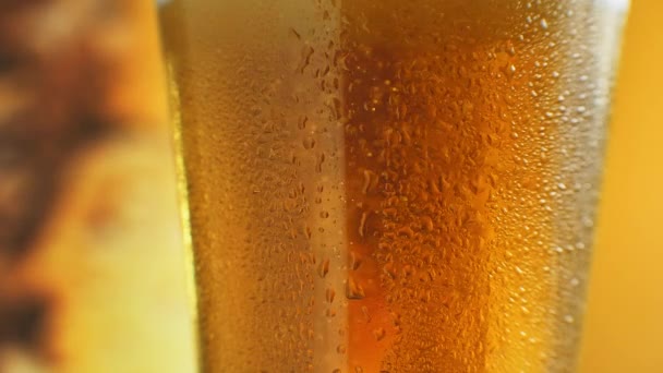 オレンジ色の液体でガラス中に上昇微泡のマクロショット.水滴のついたガラスの中の冷たいライトビール。クラフトビールを閉じます。360度回転 - 映像、動画