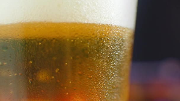 Zeitlupe aus nächster Nähe: Kaltes Bier im Glas, große Tropfen und Blasen im Bier. - Filmmaterial, Video