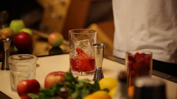 Barman stirs a thin spoon with a cocktail in a glass with ice - Footage, Video