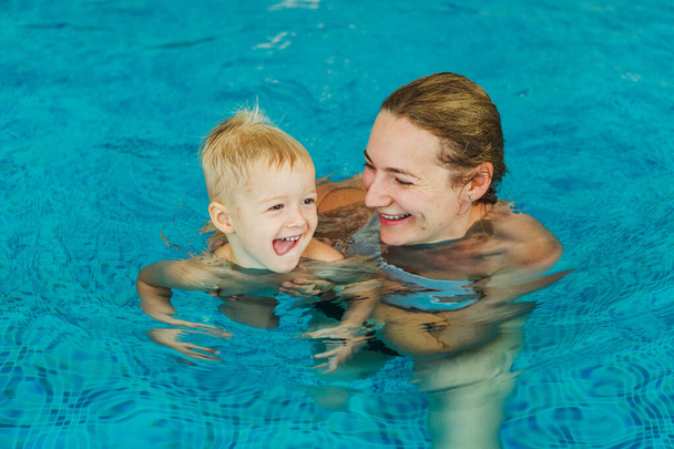 Swimming pool. Mom teaches a young child to swim in the pool. - Foto, Imagem