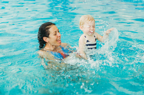 Medence. Anya tanít egy kisgyerek úszni a medencében. - Fotó, kép