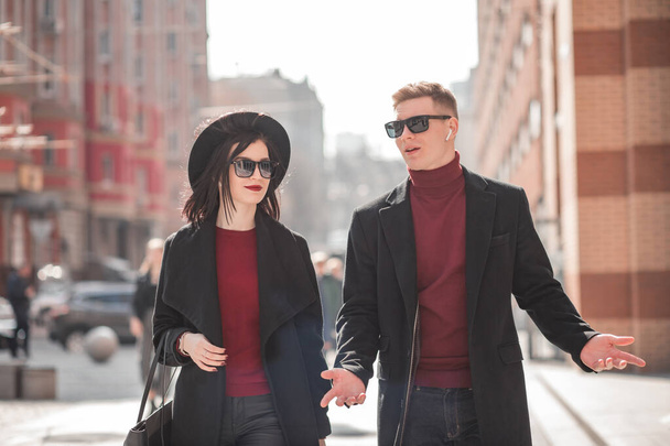 mladý muž a krásná mladá žena v černém kráčí po ulici mluví - Fotografie, Obrázek
