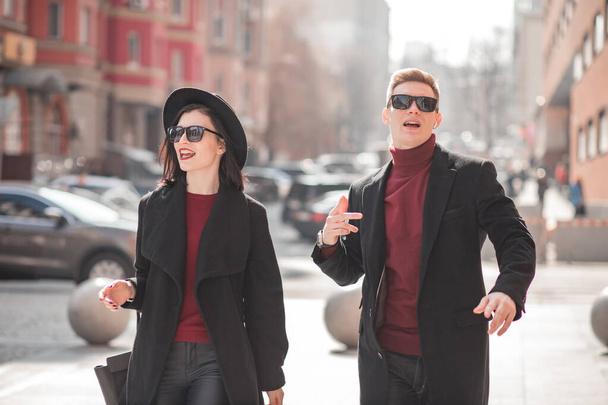 young man and beautiful young woman in black are walking on the street talking - Photo, Image