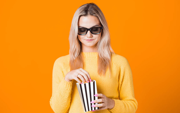 Jonge vrolijke vrouw in 3D bril kijken naar een film en het eten van popcorn. - Foto, afbeelding