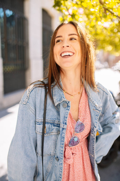 Portrait of stylish smiling happy young woman in the street with - Zdjęcie, obraz