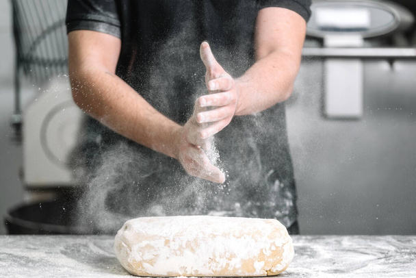 Baker applaudir les mains avec de la farine dans la cuisine du restaurant
. - Photo, image