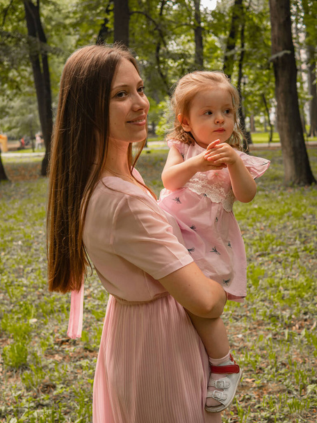 Mom and daughter walk and play in the park. Dressed in dresses. Sunny day, weekend in a city park. - Foto, Bild