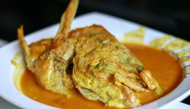 Snapper hoofd gulai (curry) op zwarte achtergrond. Gulai is een levensmiddel dat rijke, kruidige en sappige curry bevat.. - Foto, afbeelding