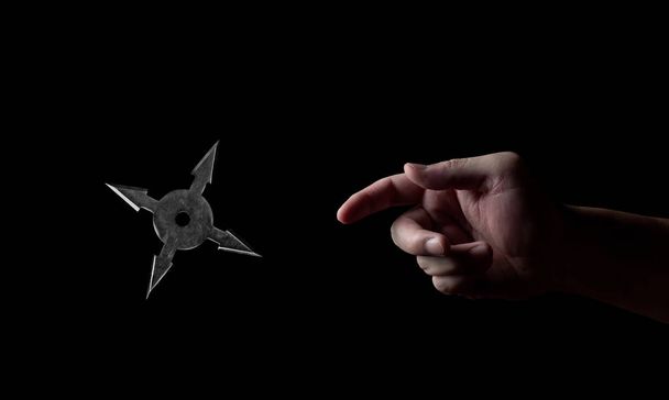 Close up Hand Throwing Ninja Star Shuriken Isolated on Black Bac - Photo, Image