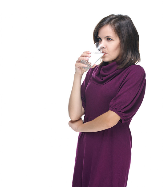 Attractive young woman in a red dress. Drinking mineral water. - 写真・画像