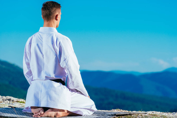 Karate master meditointi päälle vuoren yllään kimono whi
 - Valokuva, kuva