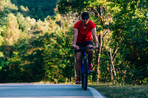 Велосипедист ездит на велосипеде по пустой дороге в природе
  - Фото, изображение