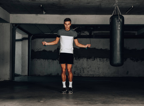 Portrait of a young sportsman in the sportwear skipping with a jumping rope - Fotoğraf, Görsel