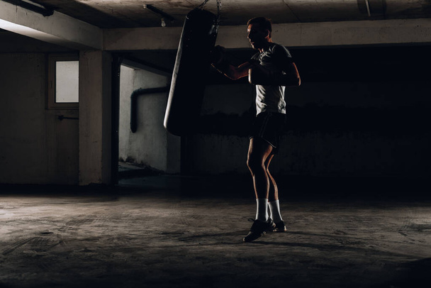 actie van een bokssport vechter training op een bokszak in de sportschool - Foto, afbeelding
