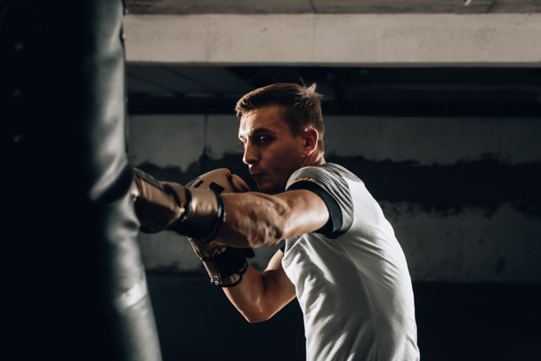 Νεαρός αθλητής πυγμαχίας προπόνηση στο γυμναστήριο σε σκούρο φόντο.Αθλητικός άνθρωπος προπόνηση hard.Kick έννοια πυγμαχίας - Φωτογραφία, εικόνα