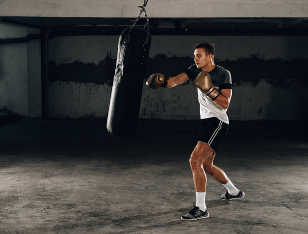 Young man athlete boxing workout in fitness gym on dark background.Athletic man training hard.Kick boxing concept - Foto, Bild