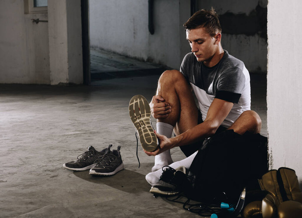 Спортивний чоловік одягаються взуття для тренувань
 - Фото, зображення