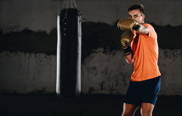 Concept of a healthy lifestyle.Young athlete fighter practicing kicks with punching bag.Kick boxer boxing as exercise for the fight - Photo, Image