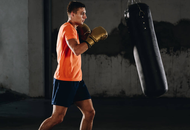 Lihaksikas nyrkkeilijä harjoittelee nyrkkeilysäkillä nyrkkeilyhanskoissa. Terveellisen elämäntavan käsite
 - Valokuva, kuva
