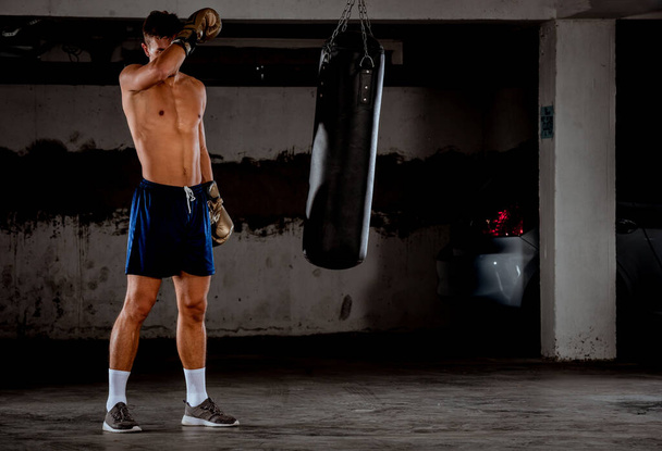 地下ガレージでのトレーニングのためのハンサムな若いボクサーの準備 - 写真・画像