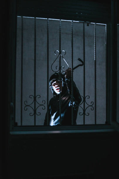Cambrioleur portant des vêtements noirs essayant de pénétrer dans une maison
 - Photo, image