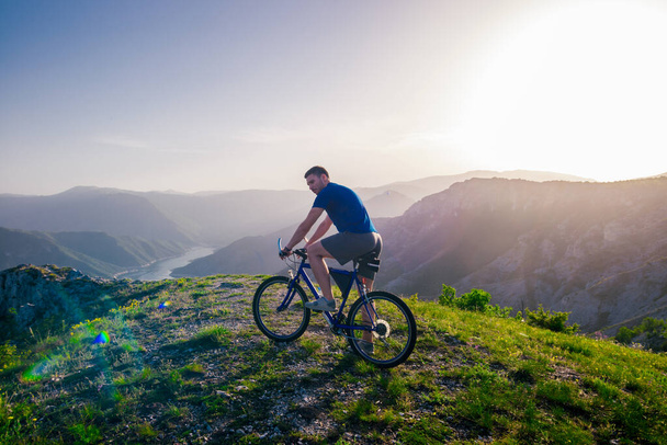 Adventurous Cyclist riding his mountain bike at the edge of a cl - Photo, Image