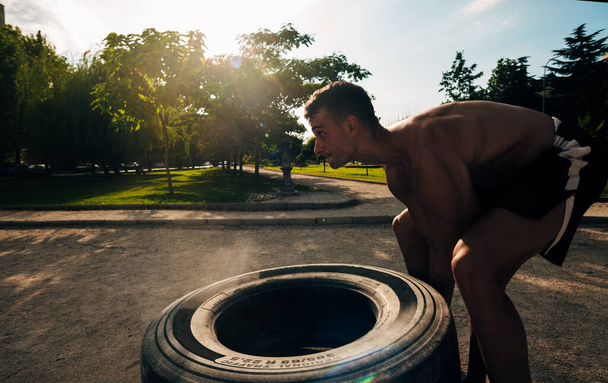concentrato giovane sportivo lanciando pneumatico pesante in palestra
 - Foto, immagini