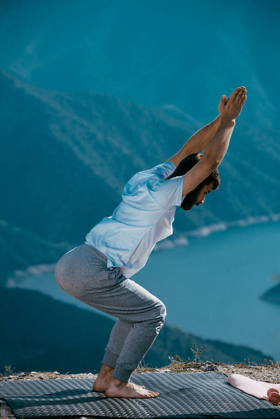 Yoga practice exercise class concept. Young man doing exercise. Man practicing yoga at mountain. - Foto, imagen