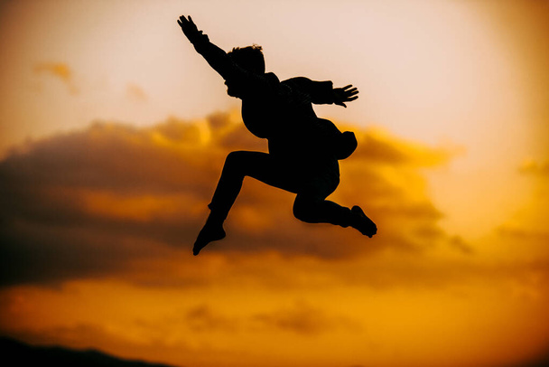 Красивий активний молодий чоловік танцює під час стрибка з гірської скелі
 - Фото, зображення